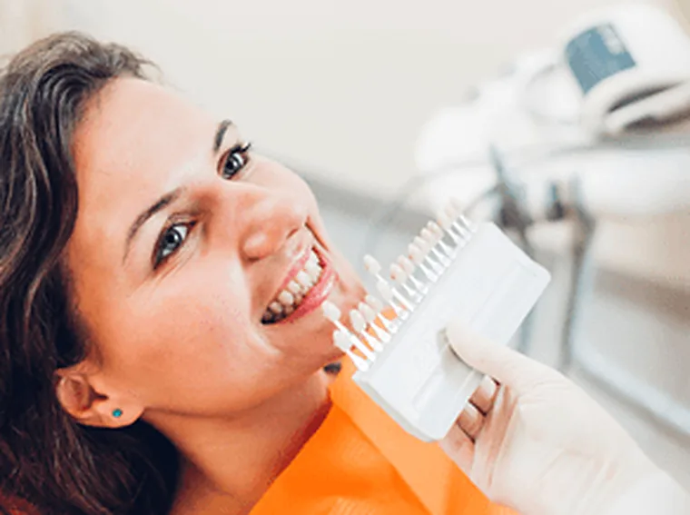 A shade guide held against a patient’s teeth to match a restoration.